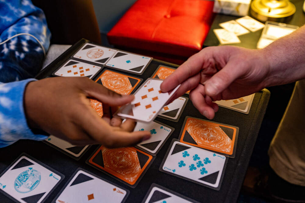 Young Adult Peer Mentor Jake Look and 16-year-old Nathanial pass cards as they play a game of Trash during a lesson at Riverside Community Care in Milford, Mass.  (Jesse Costa/WBUR)